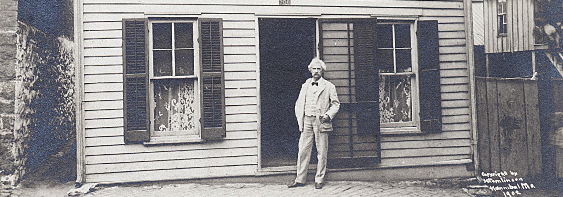 white-haired Mark Twain in front of clapboard house