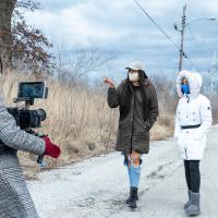 Image of filmmaker capturing footage of two women walking down an empty street with text "The Kinloch Doc"