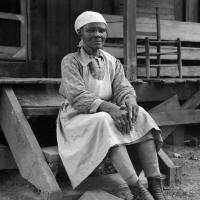 A Black woman sits on a step in front of a building