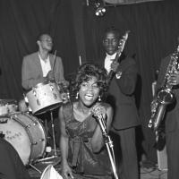 A black and white photo of the Benny Sharp Band performing. The female lead singer is in the foreground.